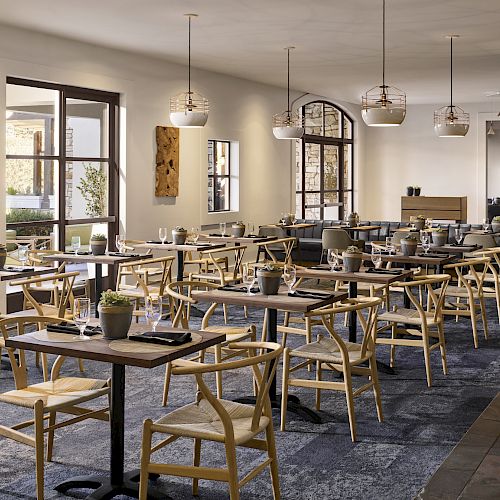 The image shows a modern, empty restaurant with wooden tables and chairs, contemporary lighting fixtures, and decorative wall art, offering a cozy ambiance.